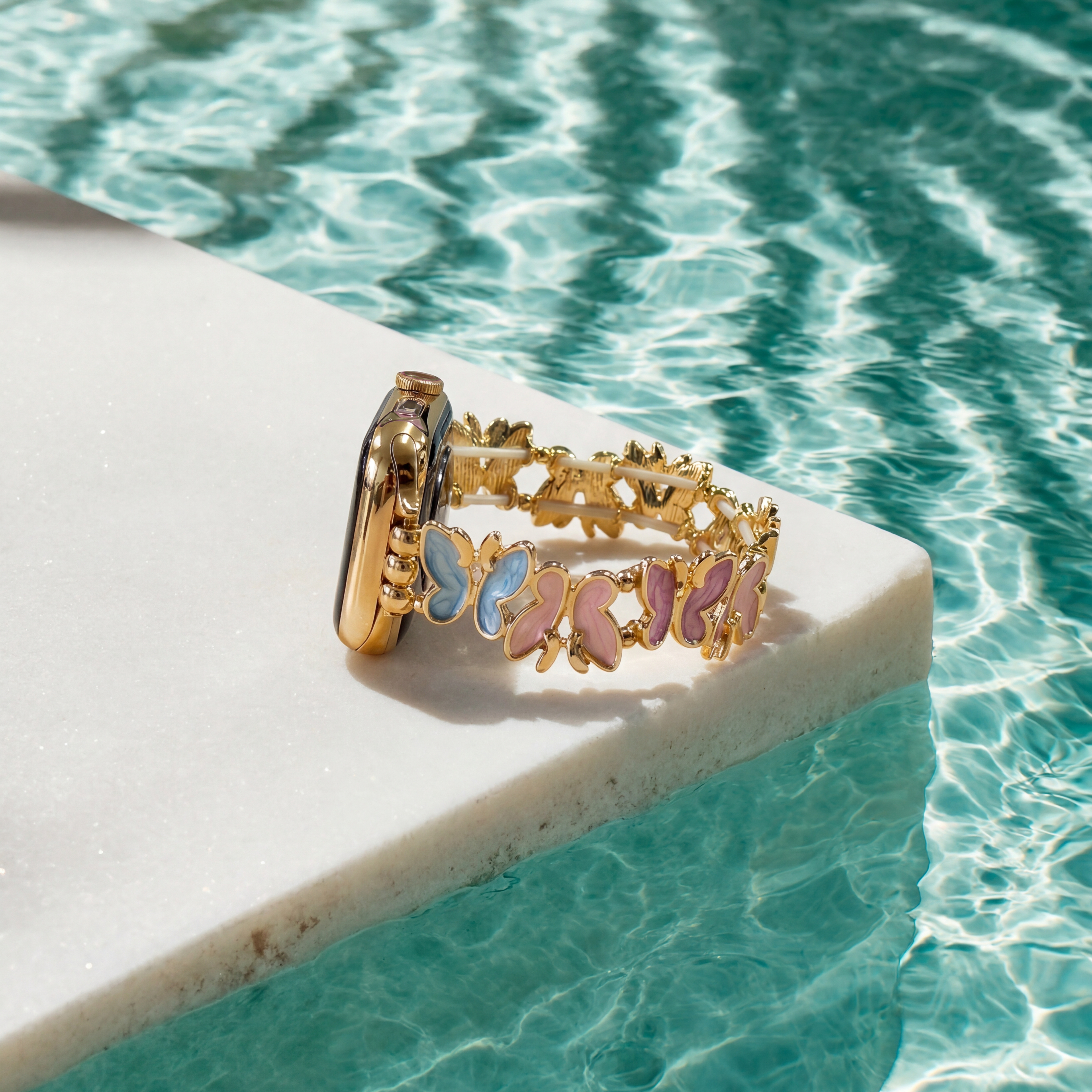 Gold ring with butterfly designs on a pool ledge