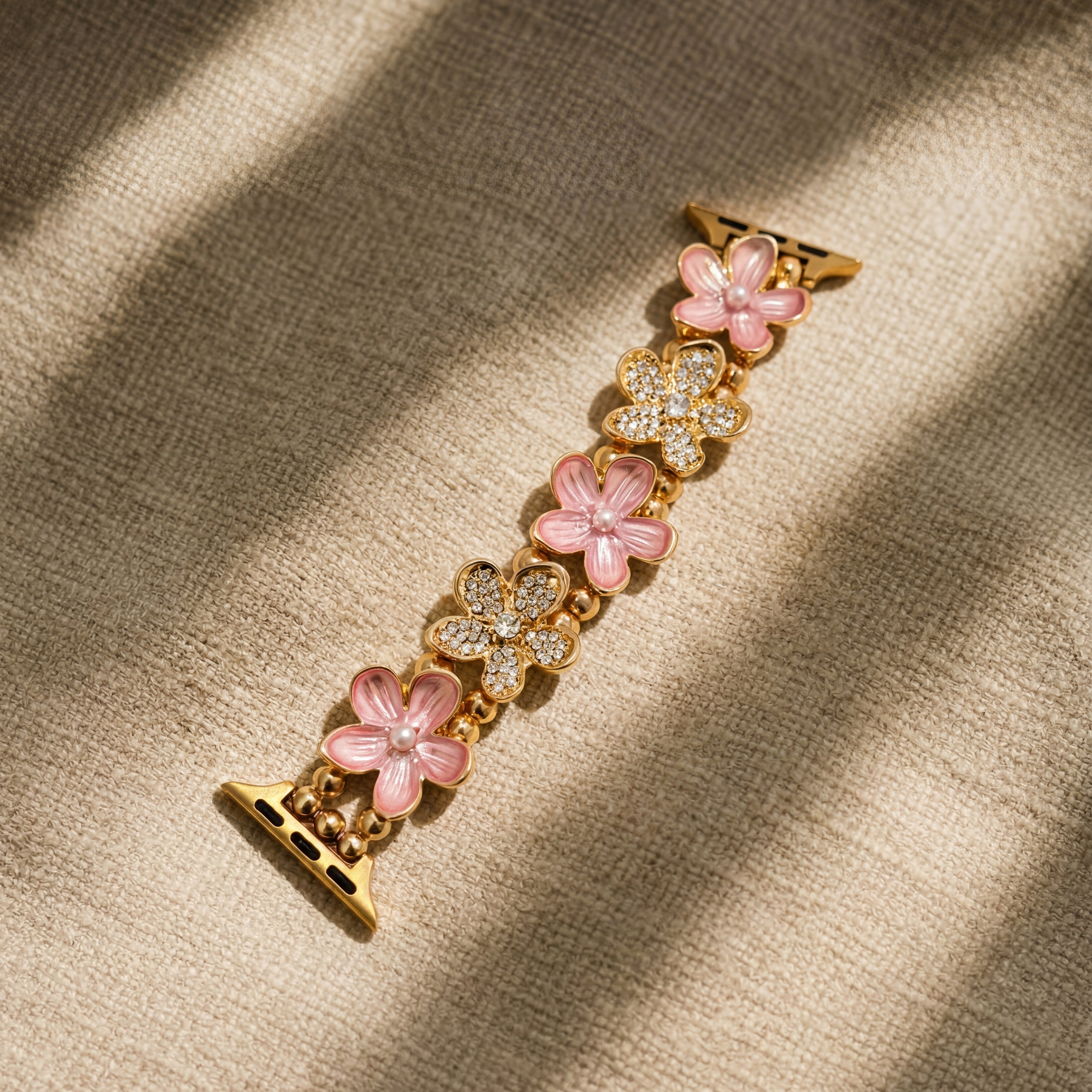 Gold watch strap with pink floral designs on a beige fabric background